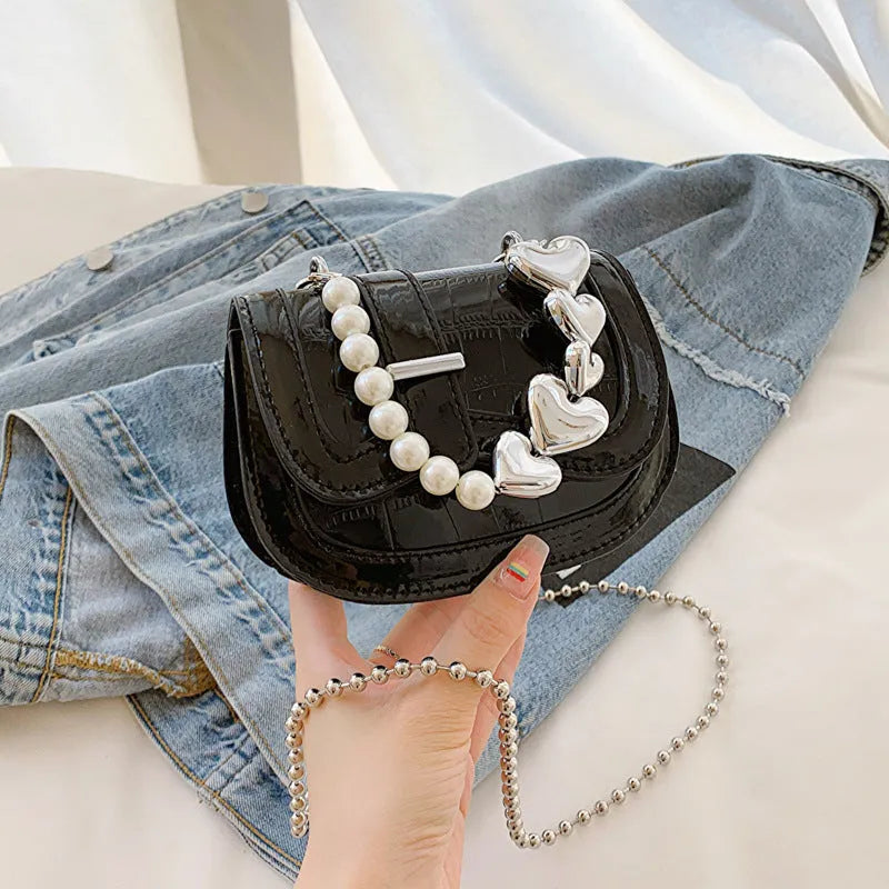 Silver laser pearl tote saddle girl mini crossbody bag with single strap on a mannequin.
