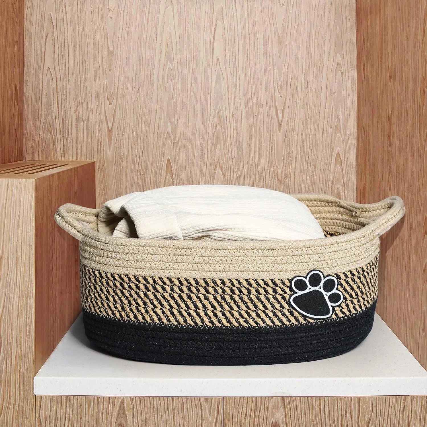 Light beige handmade woven cotton rope storage basket with handle on a wooden floor.
