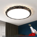 Round flush mount LED ceiling light with black iron frame on a white ceiling.