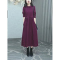 Purplish red women's plus size long sleeve dress with a long skirt, shown on a hanger.