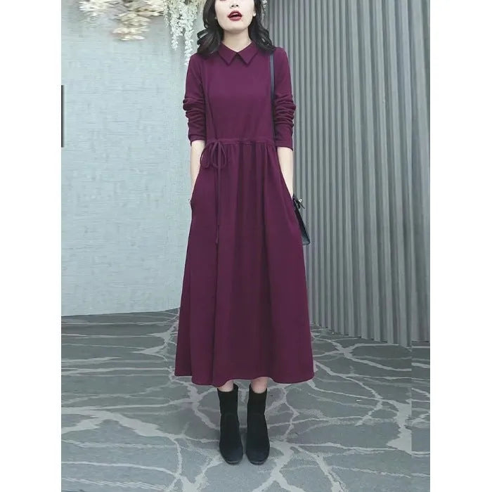 Purplish red women's plus size long sleeve dress with a long skirt, shown on a hanger.