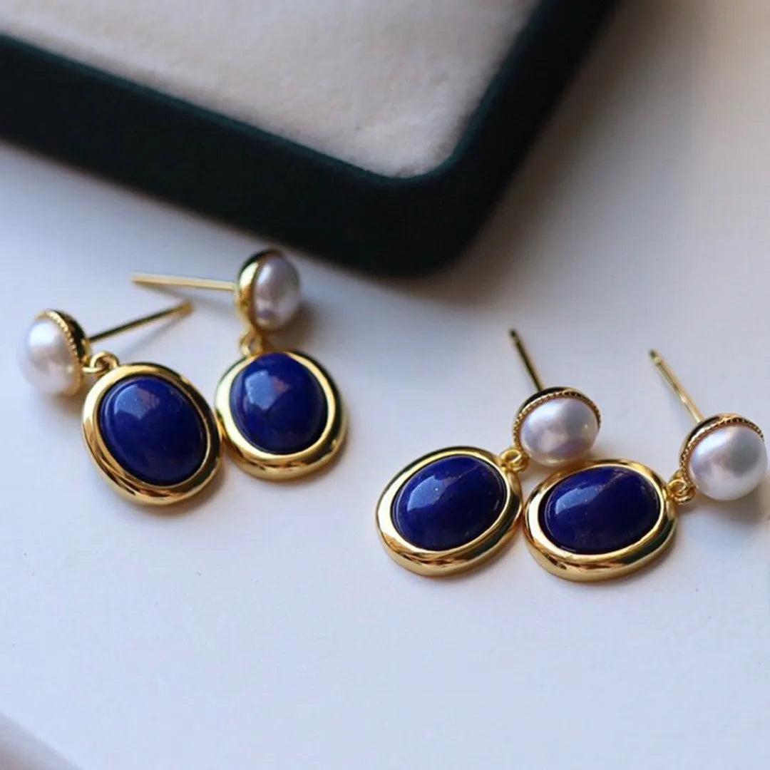 A pair of simple sterling silver stud earrings with blue lapis lazuli pearls and auspicious pattern details.