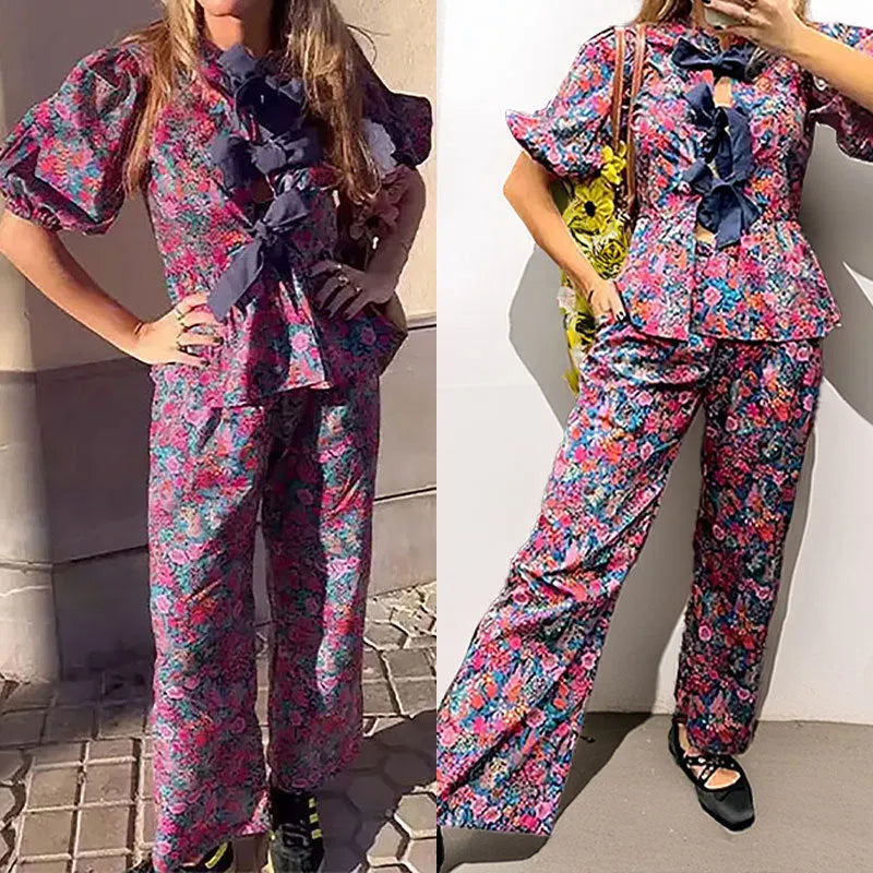 Women's floral print tie-neck blouse and trousers suit with puff sleeves.