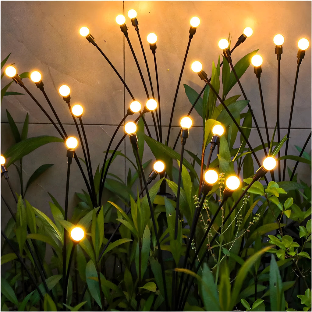 Solar-powered LED garden ground light with multiple heads and a stainless steel stake inserted into soil.