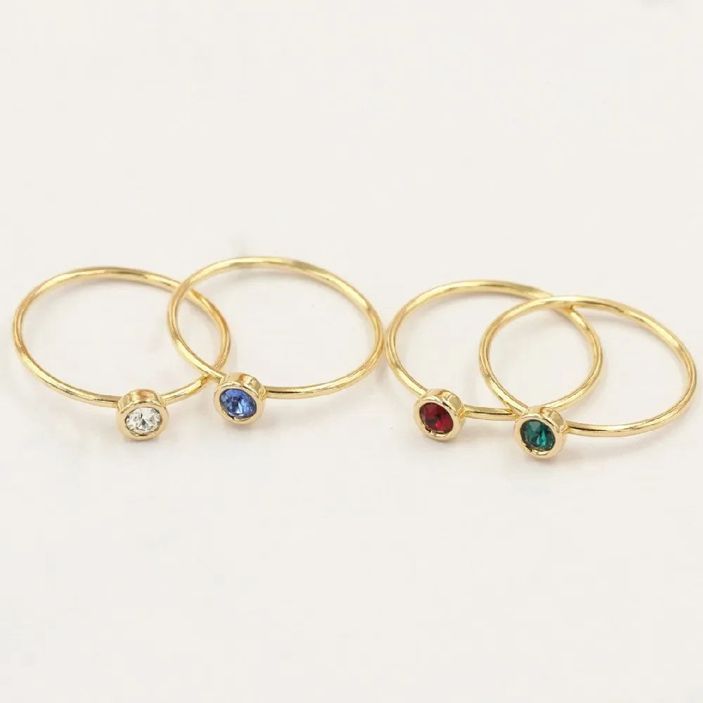 DIY knuckle ring craft kit showing 14K gold-plated ring base and green, blue, dark red, and white zircon accents.