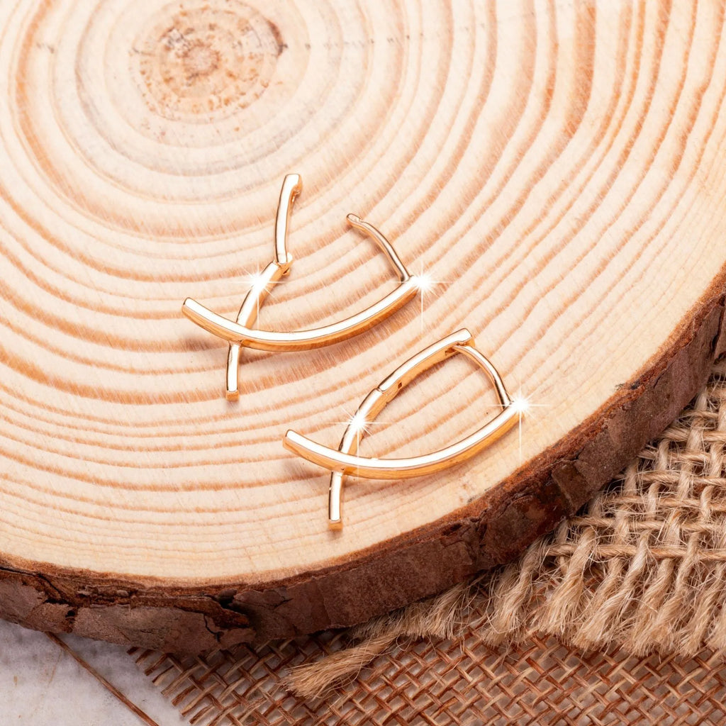 Rose gold coloured cross shaped earrings on a copper base.