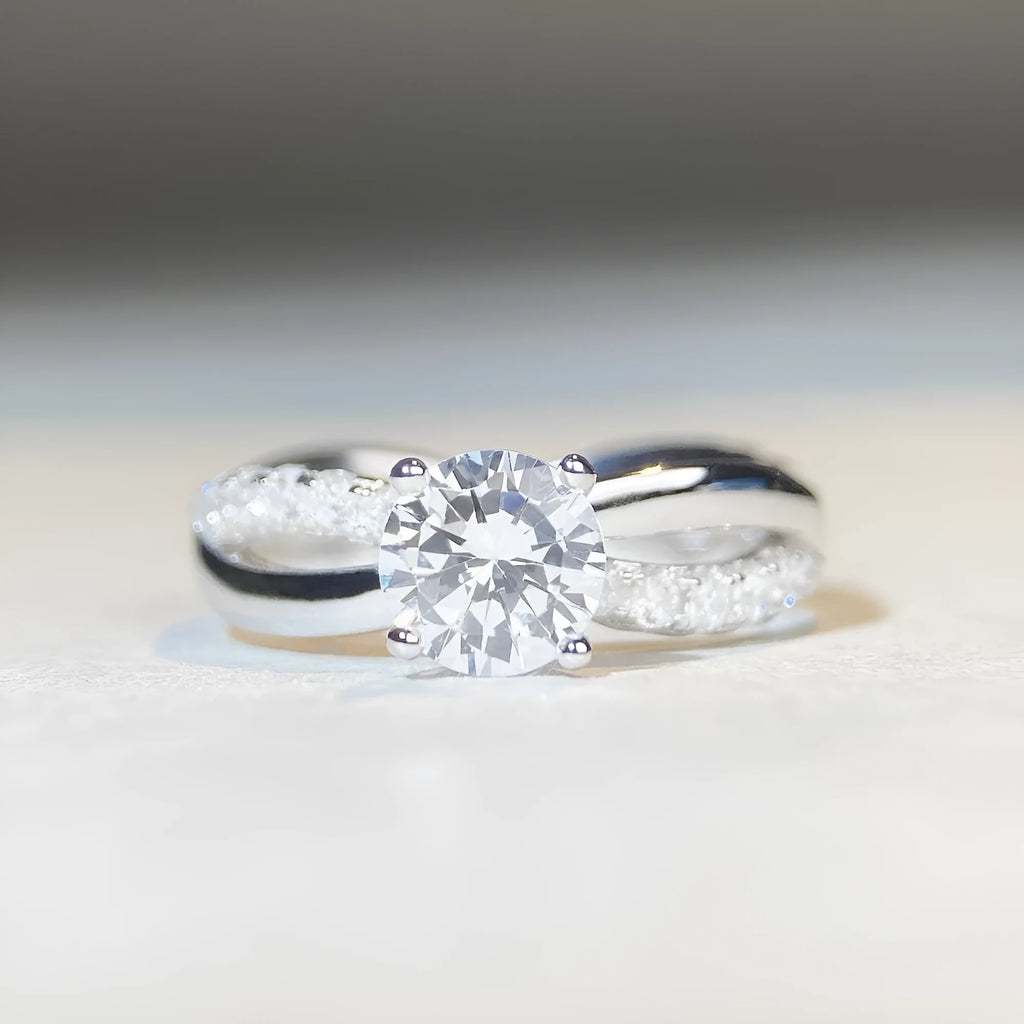Silver ring with twisted arm design and a 1 karat moissanite stone in a four-claw setting.