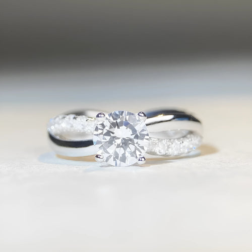 Silver ring with twisted arm design and a 1 karat moissanite stone in a four-claw setting.