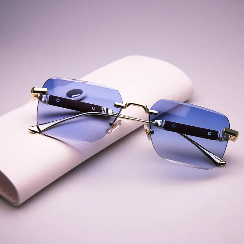 Frameless edge-cut sunglasses with gold frame, wood grain legs, and gradient grey lenses on a neutral background