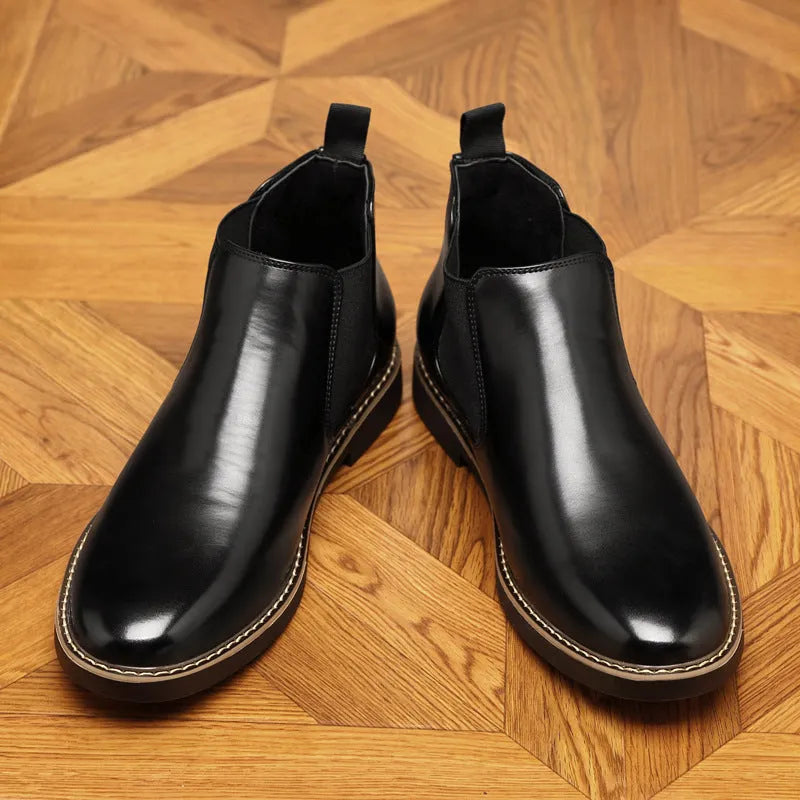 Black formal pointed-toe leather boots with a square heel and rubber sole on a neutral background.