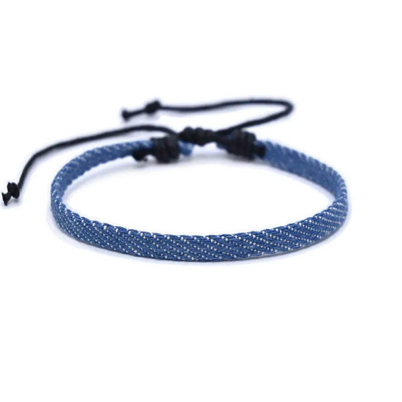 Handmade denim fabric bracelet carrying strap in national style on wrist, showing charm attachment point.