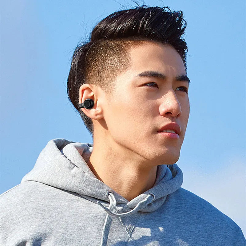 Black wireless Bluetooth clip-on headset with bone conduction technology on a white background.