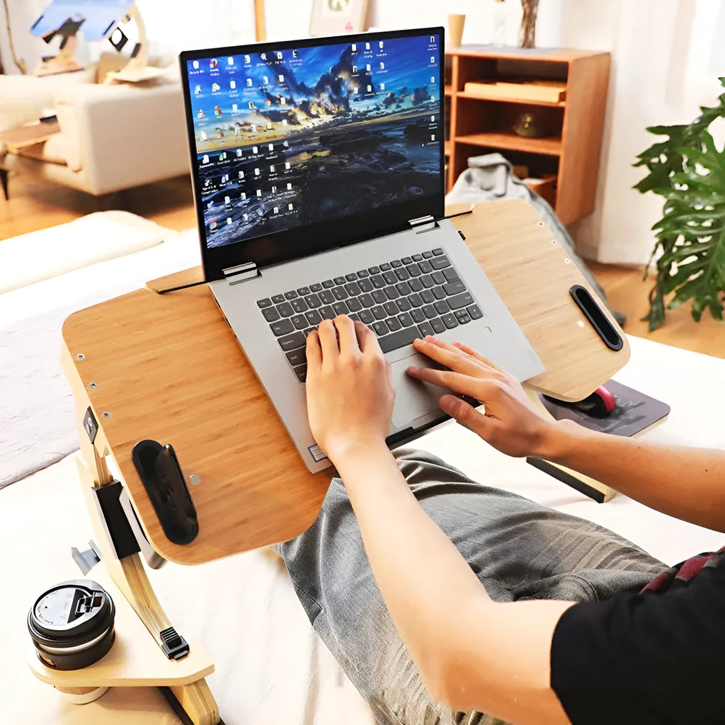 Wooden folding computer table on bed showing adjustable angle feature