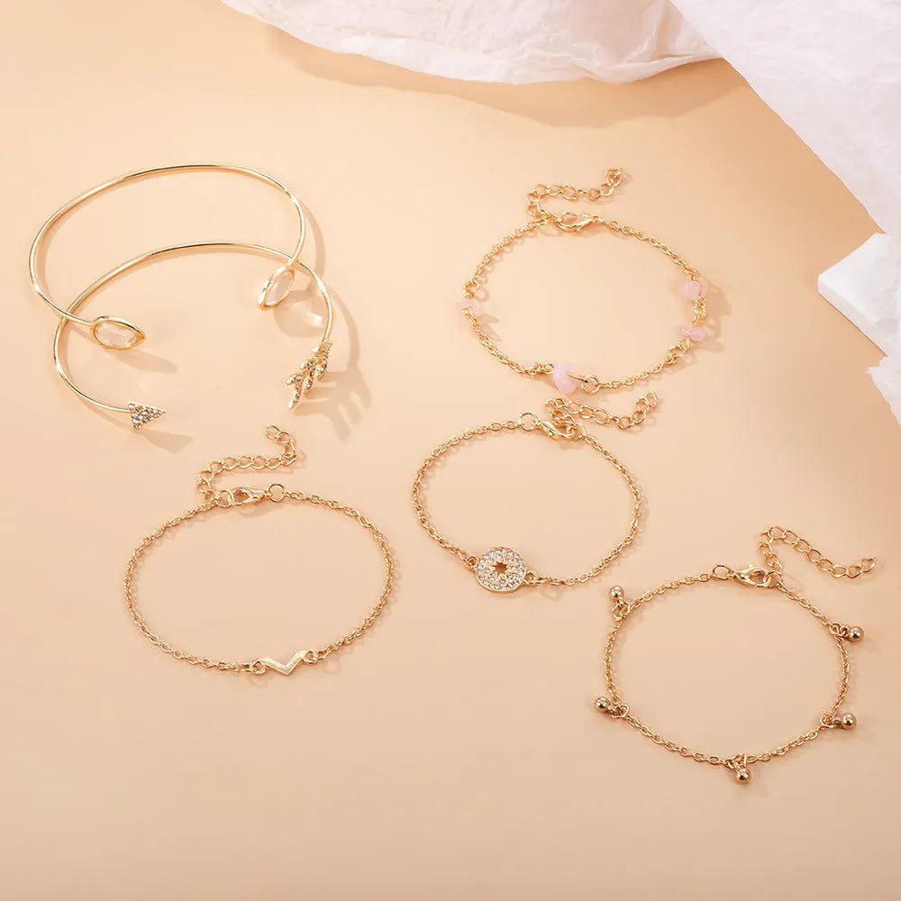 Gold-coloured women's bracelet set with six charms: arrow, water drop, and V shapes.