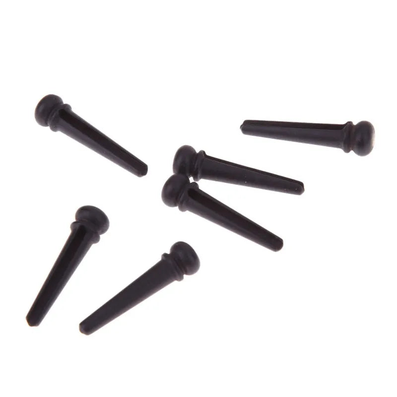 Six matt black ebony folk guitar bridge pins with 5.3mm bayonet diameter on a plain background.