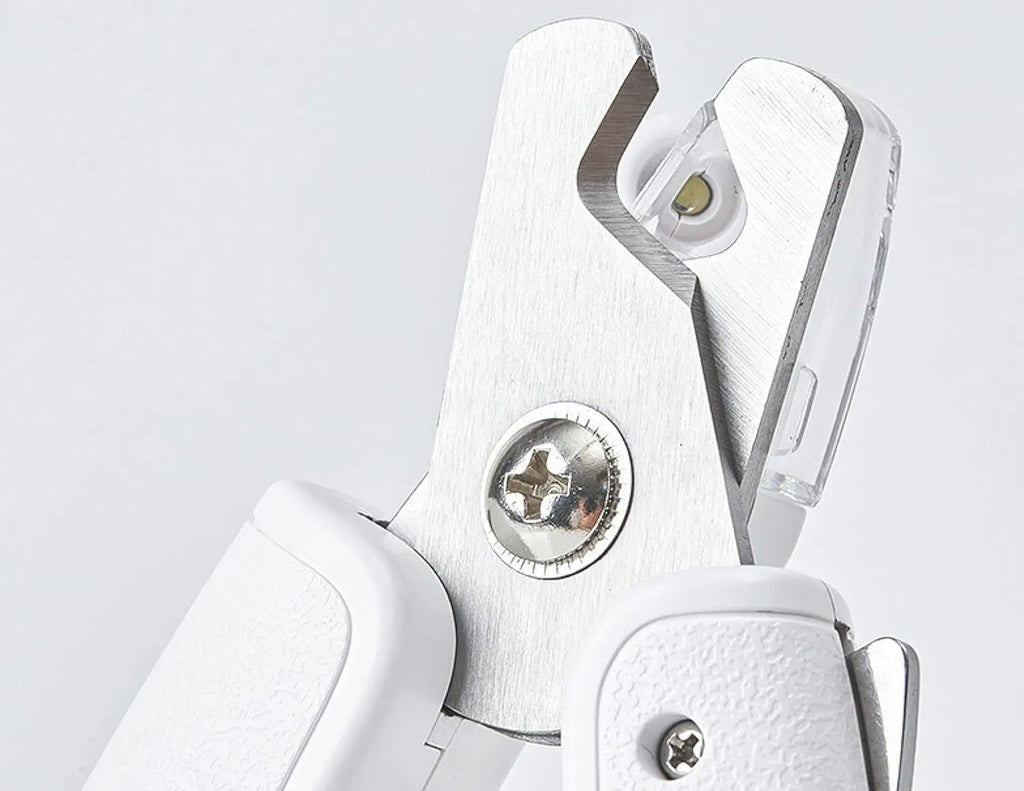 White LED pet nail clippers with transparent guard, triangular blade, and anti-slip handle next to a filing tool.