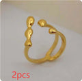 Open circle brass fashion ring with spherical beads in gold tone on a hand.