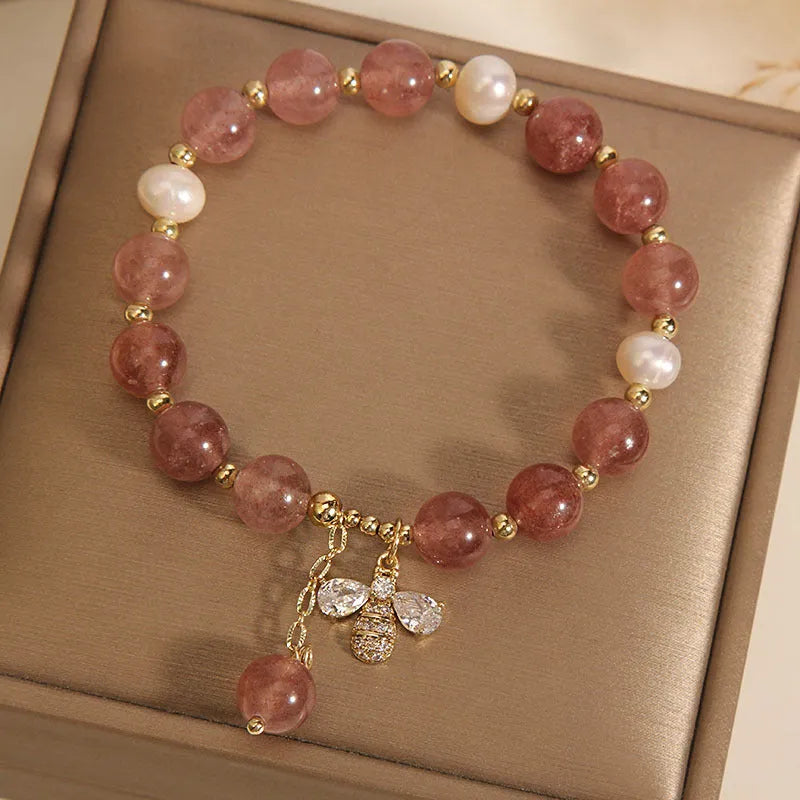 Women's bracelet with strawberry quartz beads, freshwater pearls, and a bee charm.