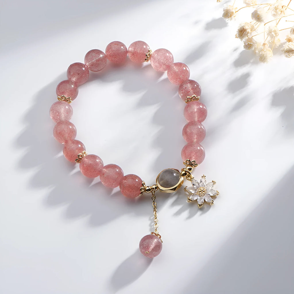 Mori style crystal bracelet with strawberry quartz stones and floral design details on a wrist.