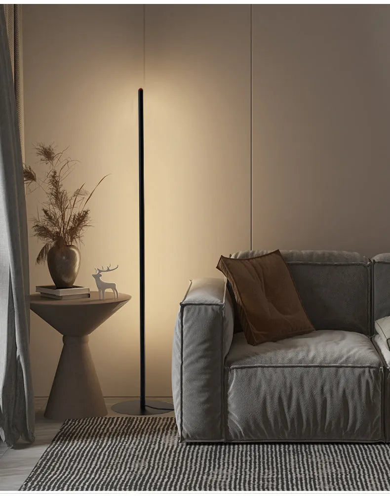 Vertical aluminium alloy floor lamp with a simple modern design, shown in a living room setting.