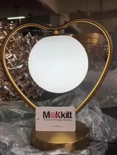 Small white heart shaped table lamp with a touch sensor base and glowing warm light.