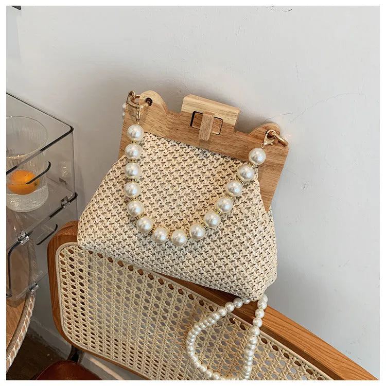 Women's straw woven shoulder bag with pearl chain detail showing interior organisation compartments