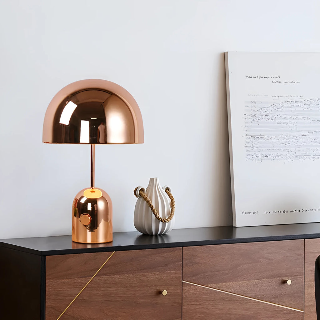 Mushroom-shaped metal table lamp in rose gold finish on a wooden table.