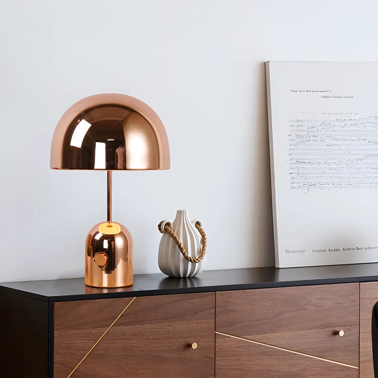 Mushroom-shaped metal table lamp in rose gold finish on a wooden table.