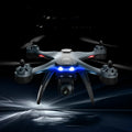 Plastic quadrocopter drone with four rotors and GPS antenna, shown with handle remote controller and spare blades