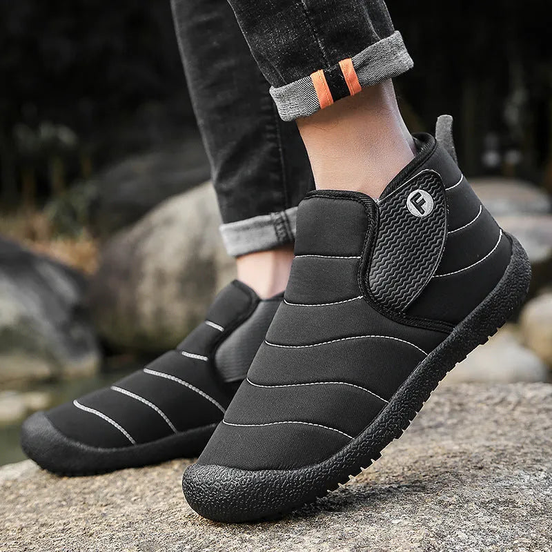 Men's black waterproof snow boot with thick sole and plush lining on a hard ground surface.
