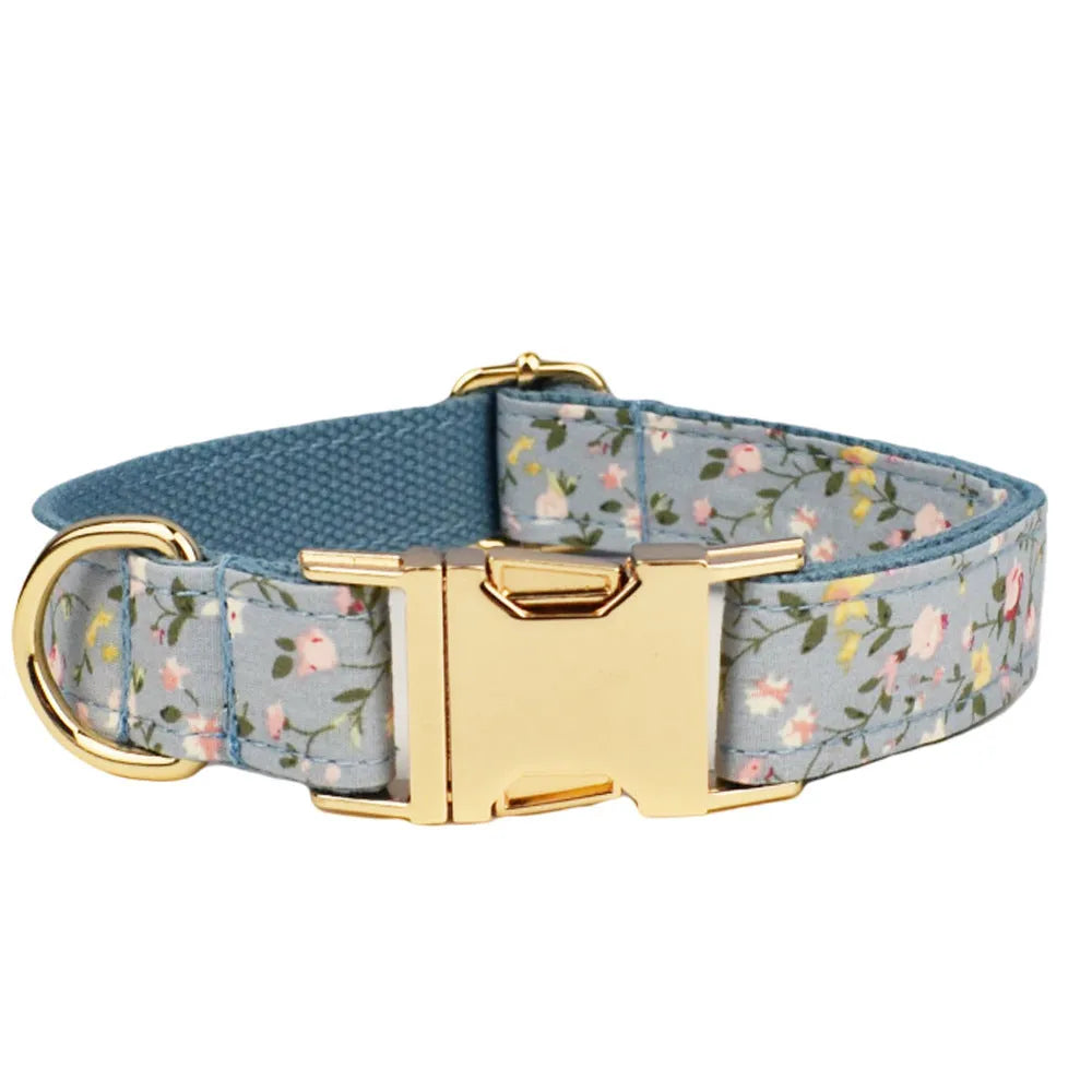 Blue floral patterned dog collar and matching leash, vest, and bow set on a white background.