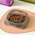 Blue plastic slow feeder dog bowl with anti-choking design on a white surface.