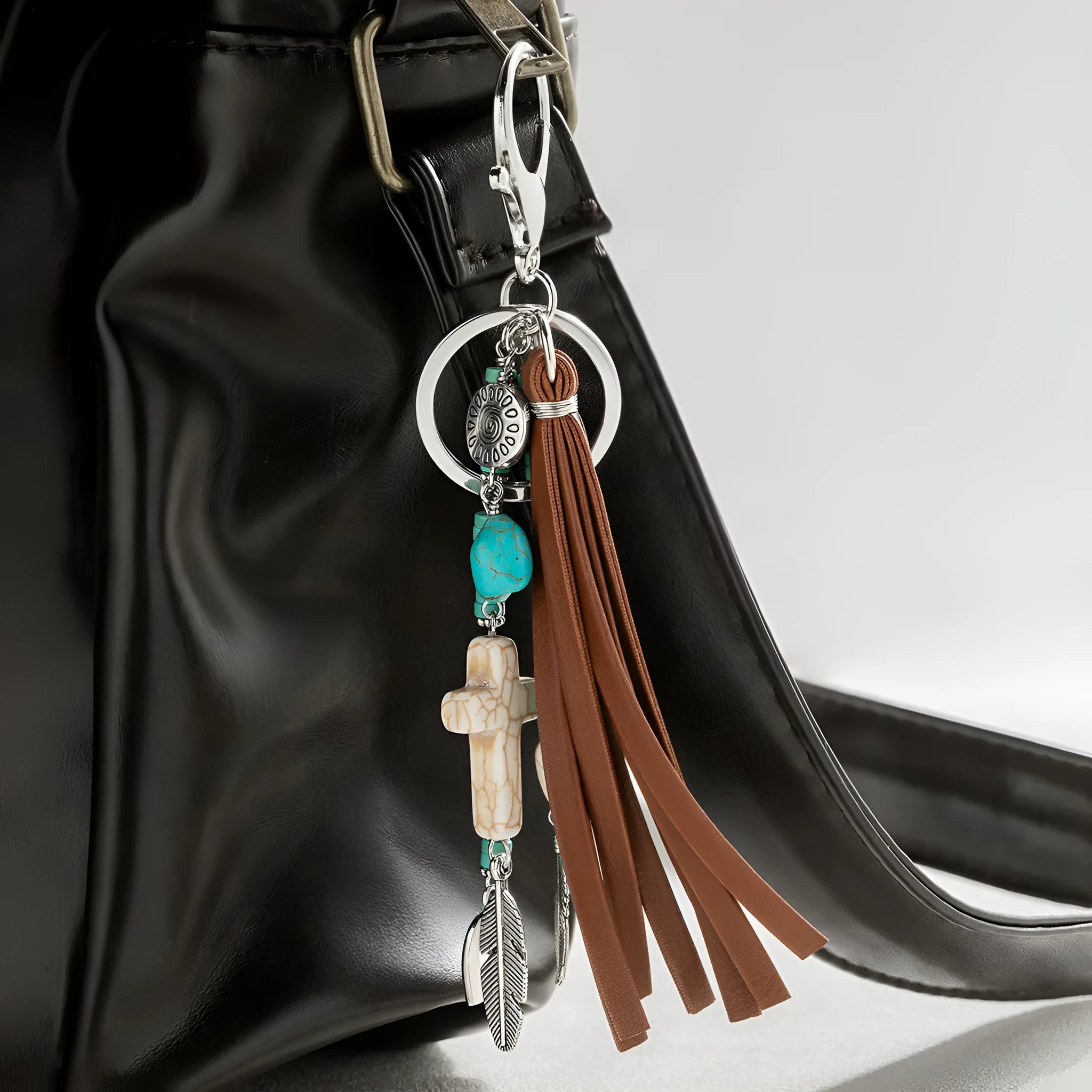 Alloy cross pendant keychain with leather rope and tassel in colour XY-3669 on a wooden surface