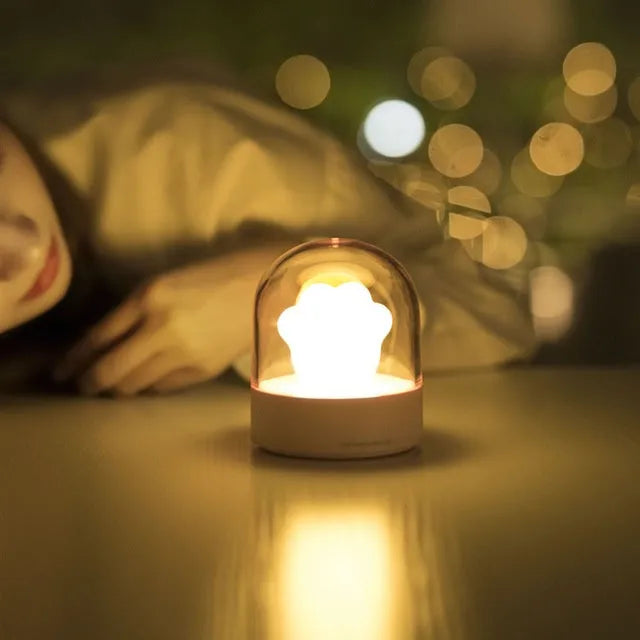 Grey cat paw shaped USB night light with rotating soft light and music box function on wooden desk