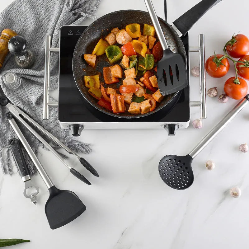 Black silicone and stainless steel kitchen spatula and spoon set, 16 pieces laid out.