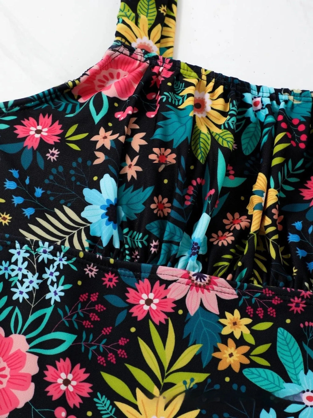 Women's floral print one-piece swimsuit on hanger showing full-bed design and polyester fabric