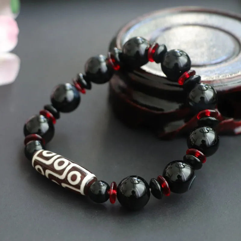 Black agate Dzi bead bracelet with hand-woven construction and geometry beads.