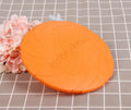 Dog training set with plastic frisbee and bite ring in orange and green colours on grass