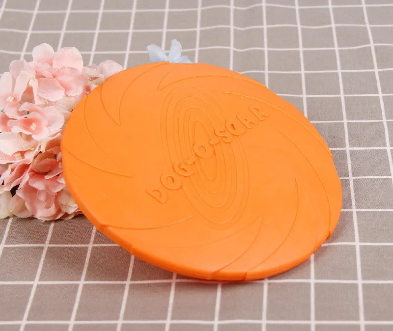 Dog training set with plastic frisbee and bite ring in orange and green colours on grass