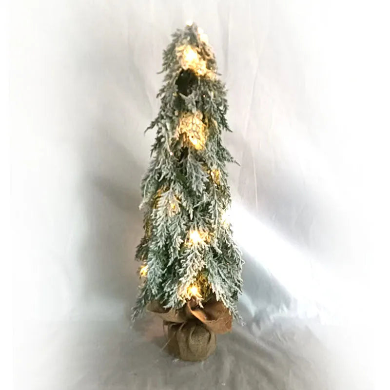 Small 24-inch artificial Christmas tree with snow sprayer finish and integrated lights on desktop