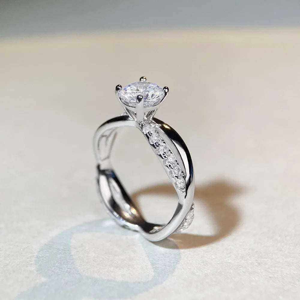 Silver ring with twisted arm design and a 1 karat moissanite stone in a four-claw setting.