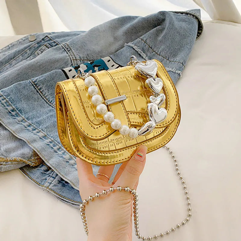 Silver laser pearl tote saddle girl mini crossbody bag with single strap on a mannequin.