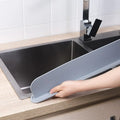 Thick grey silicone sink water blocking plate resting on a kitchen sink edge.