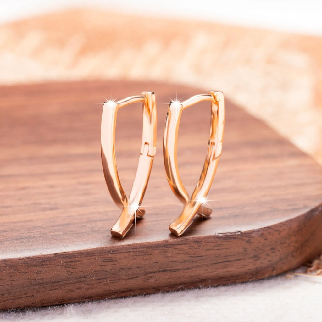 Rose gold coloured cross shaped earrings on a copper base.