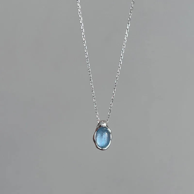 Geometric navy blue and platinum colour water drop pendant necklace on a cross chain.