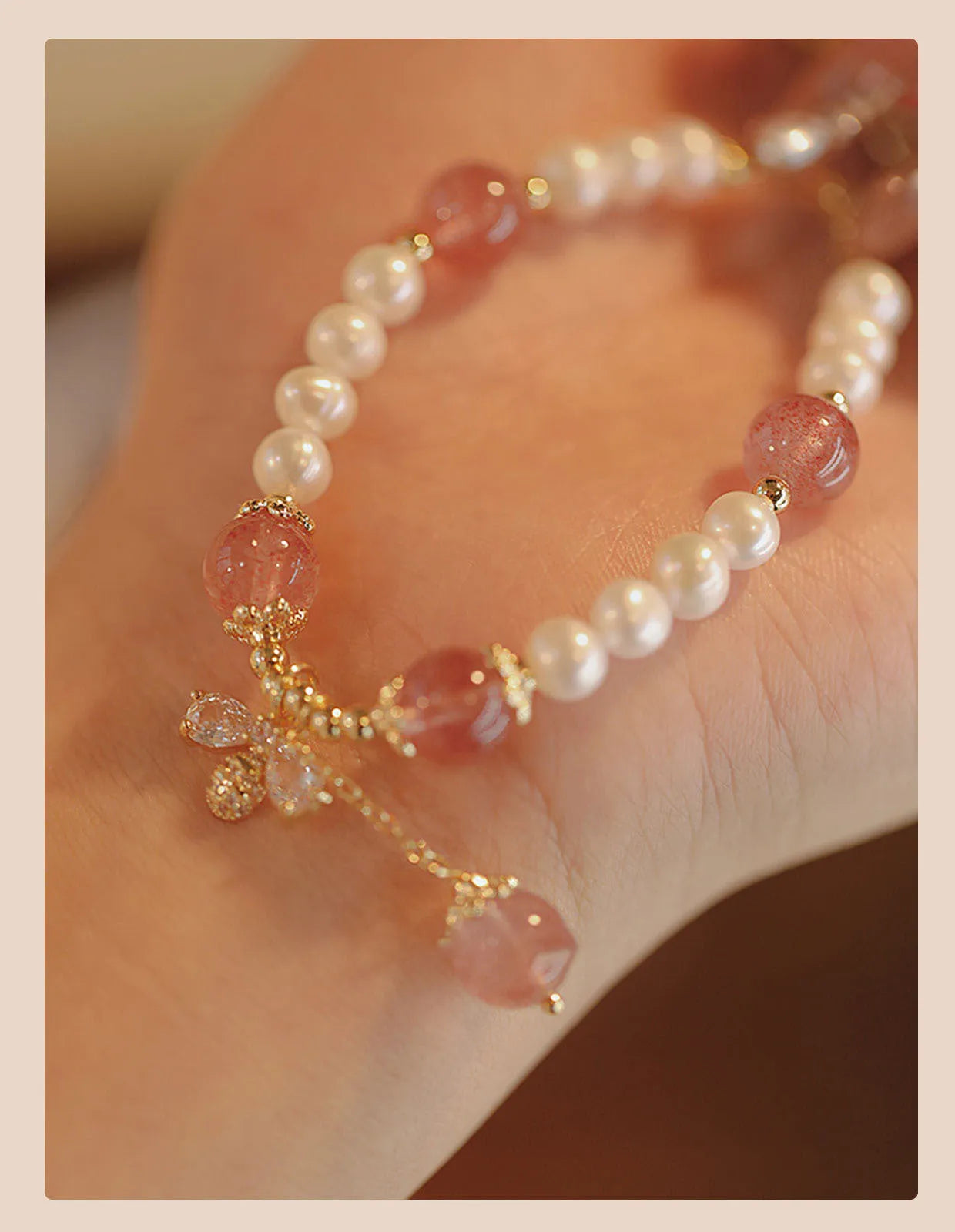 Women's handmade strawberry quartz and crystal bracelet with a decorative bow on a string of beads.