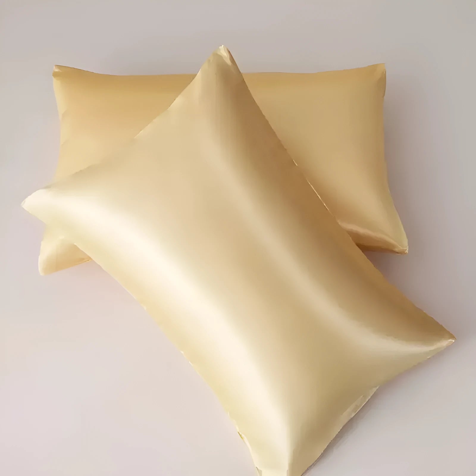 A pair of solid colour satin pillowcases in various shades on a bed.