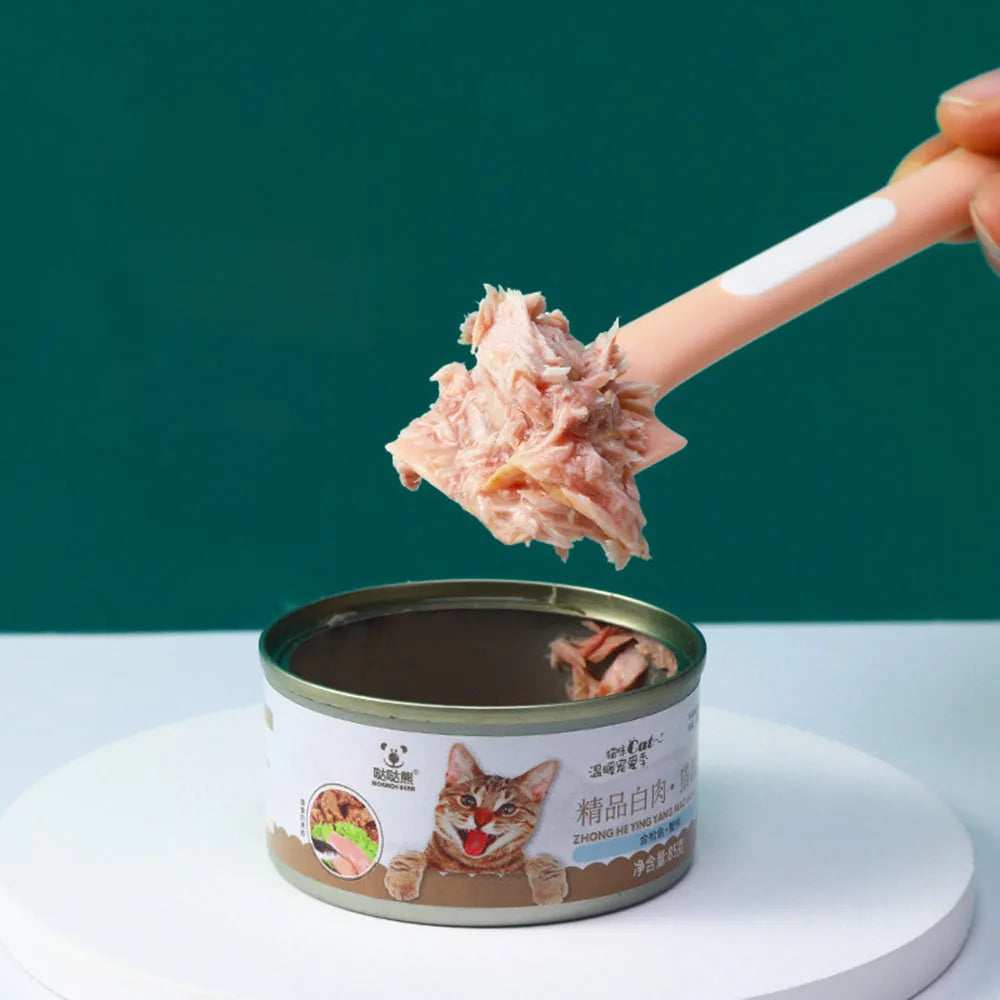 Long green handled pet food scoop next to a dog food tin, showing its right-angle scraping head.