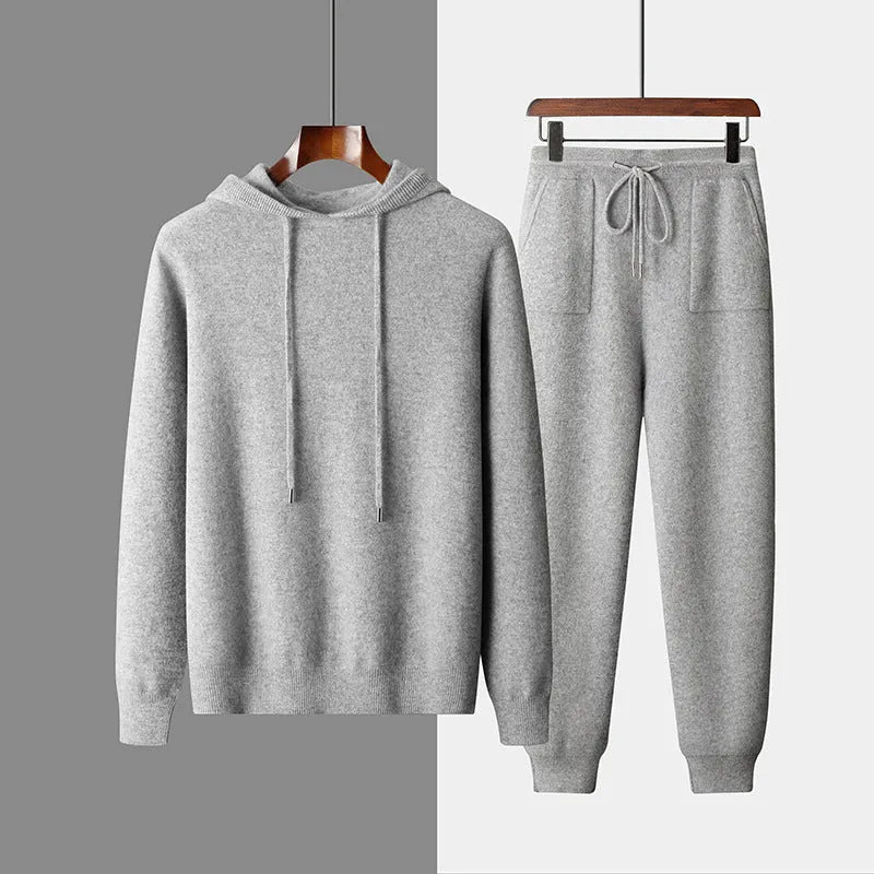 Man wearing a light grey hooded cashmere sweatshirt and matching long pants from a winter leisure set.