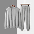 Man wearing a light grey hooded cashmere sweatshirt and matching long pants from a winter leisure set.